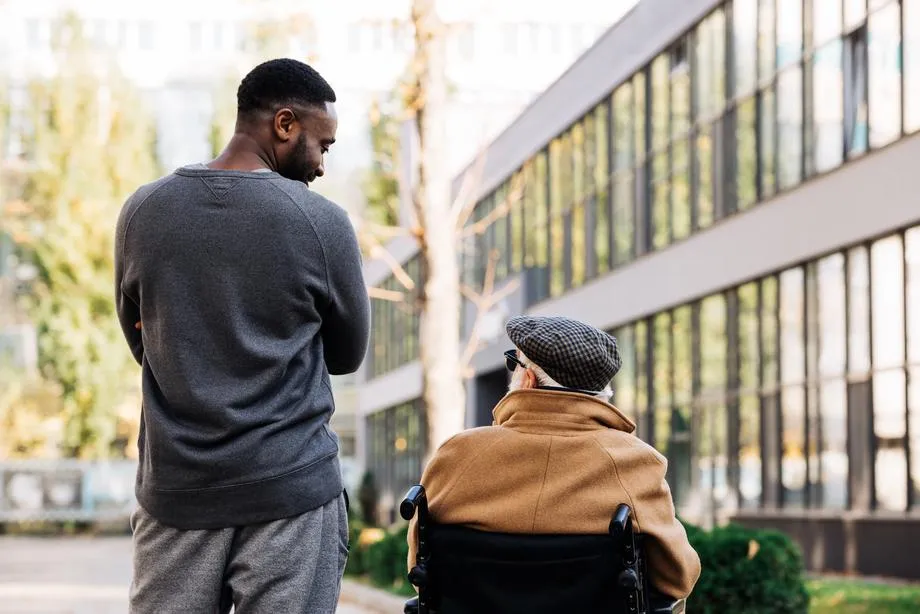 man standing and looking at man in wheelchair